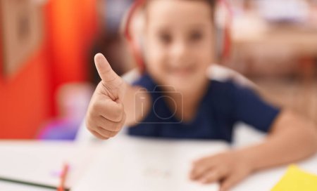 Foto de Adorable estudiante hispano niño sonriendo confiado haciendo buen gesto con el dedo en el aula - Imagen libre de derechos