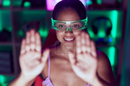 Photo for Young hispanic woman streamer using virtual reality glasses at gaming room - Royalty Free Image
