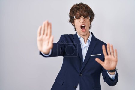 Photo for Hispanic business young man wearing glasses doing stop gesture with hands palms, angry and frustration expression - Royalty Free Image