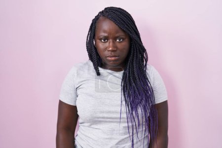 Foto de Mujer africana joven de pie sobre fondo rosa escéptico y nervioso, frunciendo el ceño molesto debido a un problema. persona negativa. - Imagen libre de derechos