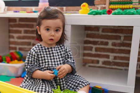 Photo for Adorable chinese girl playing with construction blocks sitting on floor at kindergarten - Royalty Free Image