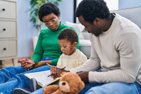 Photo for African american family drawing on notebook sitting on floor at home - Royalty Free Image