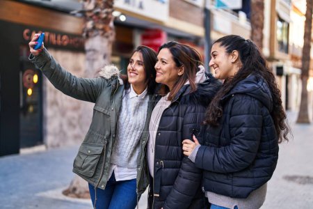 Photo for Three woman mother and daughters make selfie by the smartphone at street - Royalty Free Image