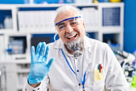 Photo for Middle age man with grey hair working at scientist laboratory looking positive and happy standing and smiling with a confident smile showing teeth - Royalty Free Image