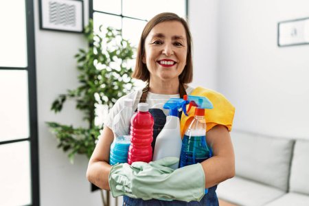 Photo for Middle age hispanic woman working as housekeeper holding products at home - Royalty Free Image