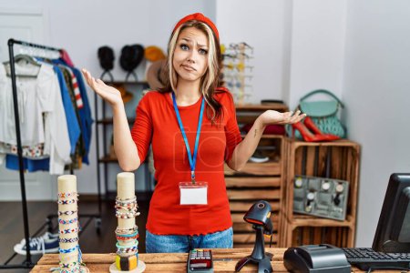 Téléchargez les photos : Jeune femme caucasienne qui travaille comme directrice à la boutique de détail expression désemparée et confuse avec les bras et les mains levées. concept de doute. - en image libre de droit