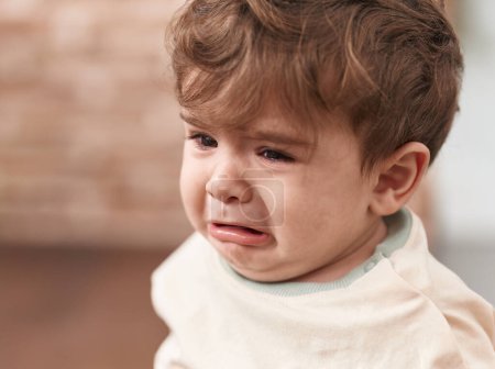 Photo for Adorable hispanic toddler sitting on floor crying at home - Royalty Free Image