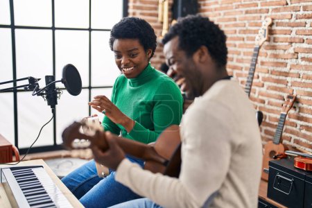 Téléchargez les photos : African american man and woman music group chant chanson jouant de la guitare et du tambourin au studio de musique - en image libre de droit