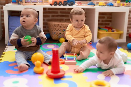 Foto de Grupo de niños pequeños jugando con juguetes sentados en el suelo en el jardín de infantes - Imagen libre de derechos