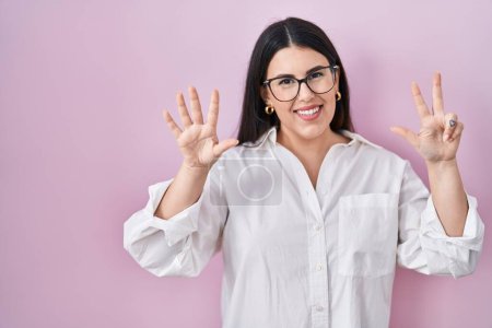 Photo for Young brunette woman standing over pink background showing and pointing up with fingers number eight while smiling confident and happy. - Royalty Free Image