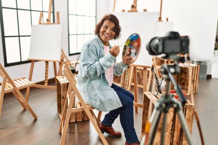 Téléchargez les photos : Moyen Age artiste hispanique blogueur souriant heureux d'avoir appel vidéo au studio d'art. - en image libre de droit