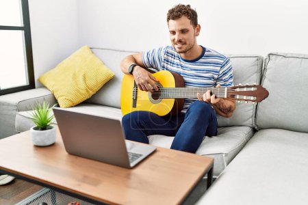 Photo for Young hispanic man smiling confident playing online guitar concert at home - Royalty Free Image