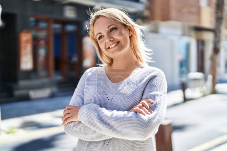 Téléchargez les photos : Jeune femme blonde debout avec les bras croisés geste à la rue - en image libre de droit