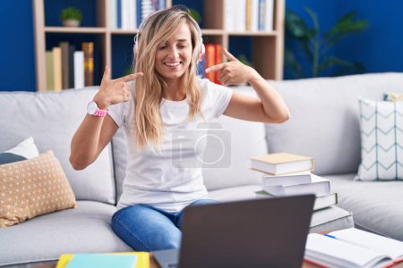 Photo for Young blonde woman studying using computer laptop at home smiling cheerful showing and pointing with fingers teeth and mouth. dental health concept. - Royalty Free Image