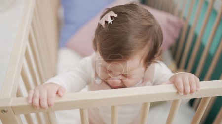Téléchargez les photos : Adorable tout-petit debout sur le berceau pleurant dans la chambre - en image libre de droit