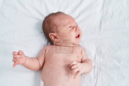 Foto de Adorable bebé caucásico acostado en la cama llorando en el dormitorio - Imagen libre de derechos
