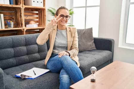 Photo for Young woman working at consultation office doing peace symbol with fingers over face, smiling cheerful showing victory - Royalty Free Image