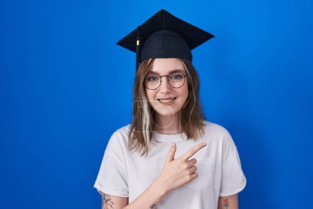 Téléchargez les photos : Blonde caucasian woman wearing graduation cap cheerful with a smile of face pointing with hand and finger up to the side with happy and natural expression on face - en image libre de droit