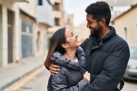 Téléchargez les photos : Homme et femme couple souriant confiant s'embrasser dans la rue - en image libre de droit