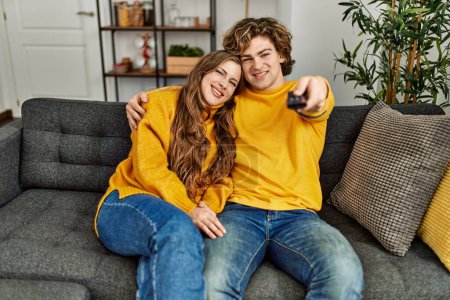 Téléchargez les photos : Jeune couple caucasien regarder film câlins à la maison - en image libre de droit