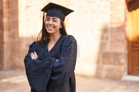 Photo for Young hispanic woman wearing graduated uniform standing with arms crossed gesture at university - Royalty Free Image