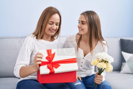 Téléchargez les photos : Deux femmes mère et fille surprise avec cadeau d'anniversaire et fleurs à la maison - en image libre de droit