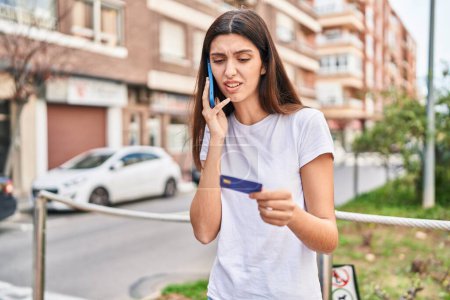 Foto de Joven mujer hispana hermosa usando teléfono inteligente y tarjeta de crédito en la calle - Imagen libre de derechos