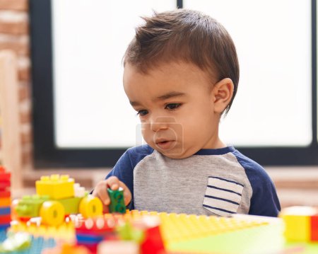 Photo for Adorable hispanic toddler playing with construction blocks standing at kindergarten - Royalty Free Image