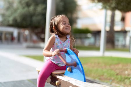 Téléchargez les photos : Adorable hispanic girl sitting on swing playing at park playground - en image libre de droit