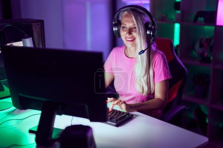 Foto de Young blonde woman streamer smiling confident using computer at gaming room - Imagen libre de derechos