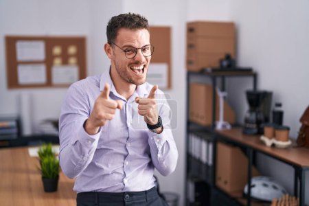 Photo for Young hispanic man at the office pointing fingers to camera with happy and funny face. good energy and vibes. - Royalty Free Image