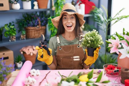 Photo for Young brunette woman working at florist shop celebrating crazy and amazed for success with open eyes screaming excited. - Royalty Free Image