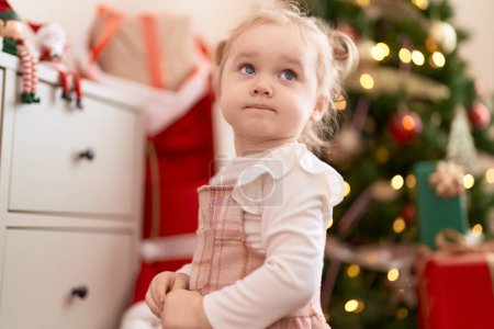 Foto de Adorable chica caucásica de pie junto al árbol de Navidad en casa - Imagen libre de derechos