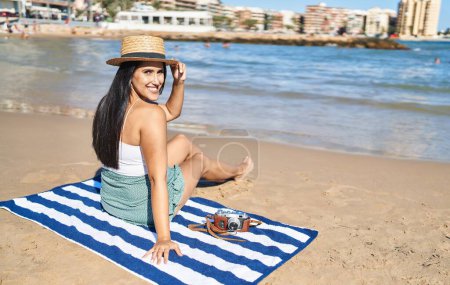 Photo for Young hispanic woman smiling confident sitting on sand at seaside - Royalty Free Image