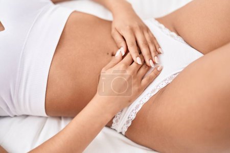 Photo for Young beautiful latin woman suffering for menstrual pain lying on bed at bedroom - Royalty Free Image