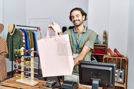 Photo for Handsome hispanic man working as shop assistance at retail shop - Royalty Free Image