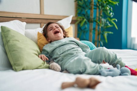 Foto de Adorable chica hispana acostada en la cama llorando en el dormitorio - Imagen libre de derechos