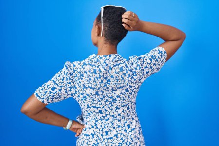 Foto de Mujer afroamericana de pie sobre fondo azul hacia atrás pensando en la duda con la mano en la cabeza - Imagen libre de derechos