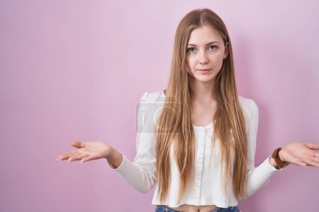 Photo for Young caucasian woman standing over pink background clueless and confused with open arms, no idea concept. - Royalty Free Image