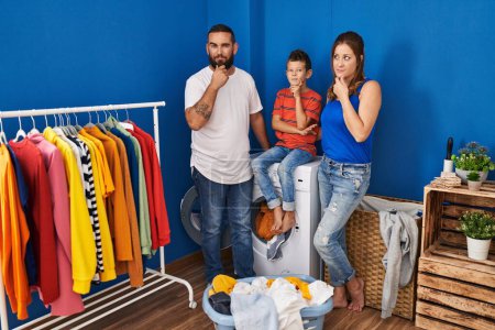 Photo for Family of three at laundry room serious face thinking about question with hand on chin, thoughtful about confusing idea - Royalty Free Image