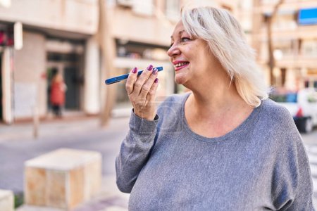 Téléchargez les photos : Middle age blonde woman smiling confident talking on the smartphone at street - en image libre de droit