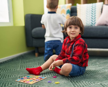 Foto de Adorable niño jugando con el juego de matemáticas sentado en el suelo en casa - Imagen libre de derechos