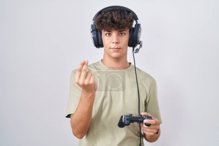 Photo for Hispanic teenager playing video game holding controller doing italian gesture with hand and fingers confident expression - Royalty Free Image
