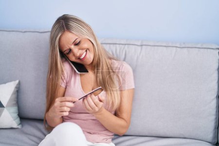 Téléchargez les photos : Jeune femme blonde parlant sur le smartphone faire manucure à la maison - en image libre de droit