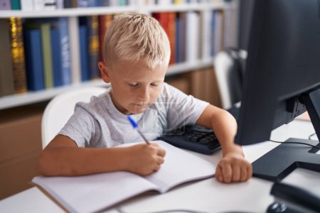 Foto de Adorable estudiante de niños pequeños utilizando la escritura por computadora en el cuaderno en el aula - Imagen libre de derechos