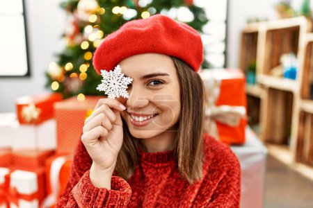Photo for Young hispanic girl holding star christmas decor over eye sitting on the floor at home. - Royalty Free Image