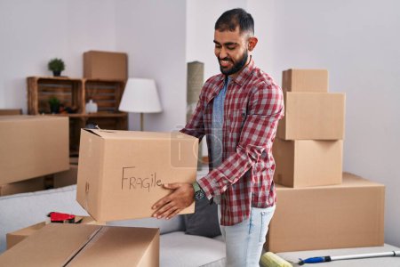 Photo for Young hispanic man smiling confident holding fragile package at new home - Royalty Free Image
