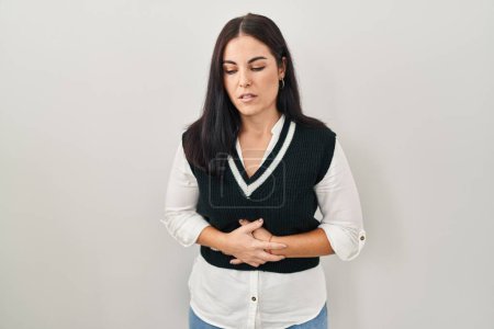 Photo for Young hispanic woman standing over isolated background with hand on stomach because indigestion, painful illness feeling unwell. ache concept. - Royalty Free Image