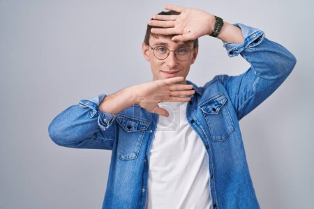 Photo for Caucasian blond man standing wearing glasses smiling cheerful playing peek a boo with hands showing face. surprised and exited - Royalty Free Image