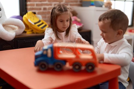 Téléchargez les photos : Adorable fille et garçon jouant avec des jouets sur la table à la maternelle - en image libre de droit